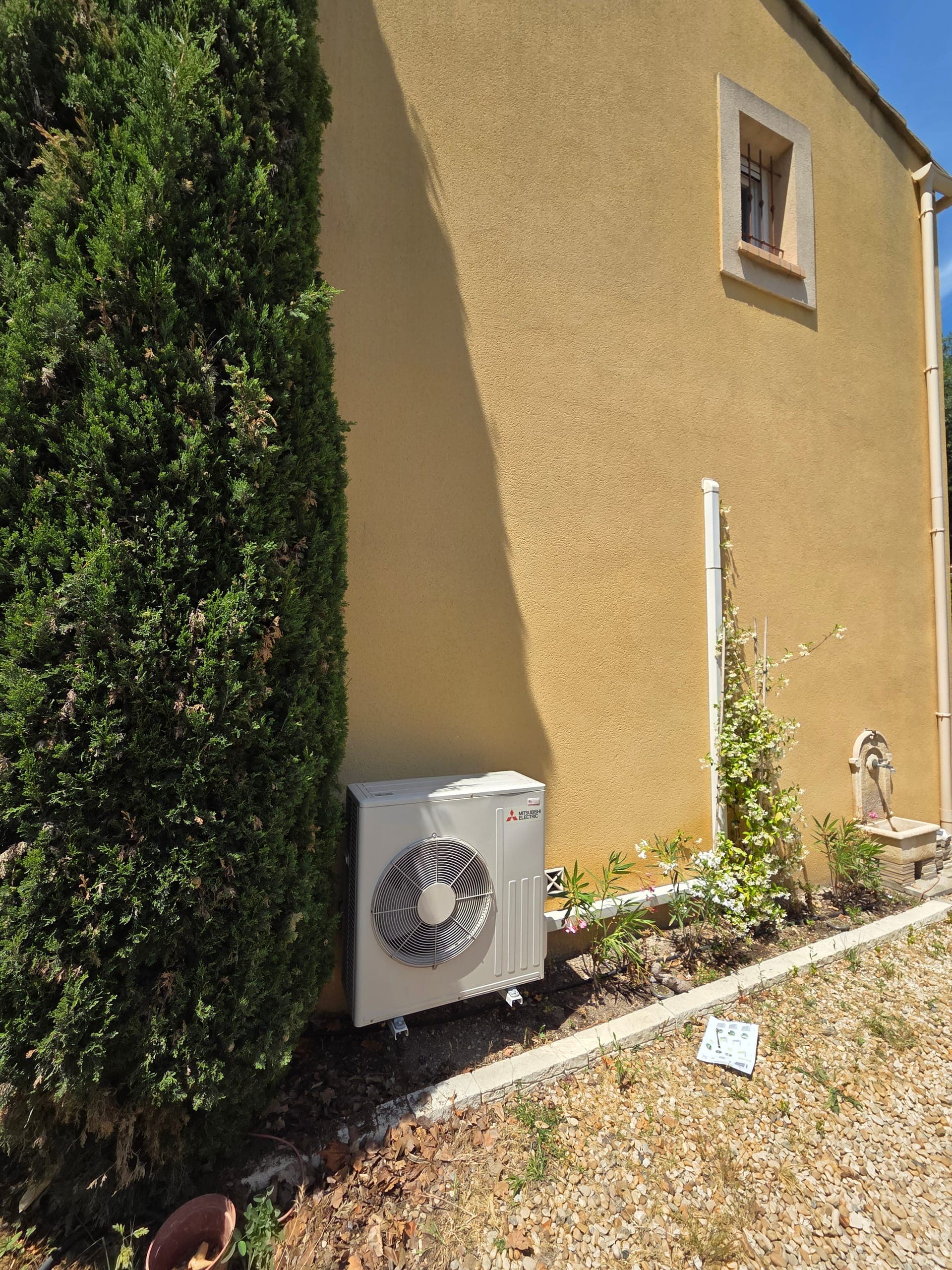 Groupe extérieur de climatisation Mitsubishi nu devant un mur ocre, avant pose de l'habillage aluminium