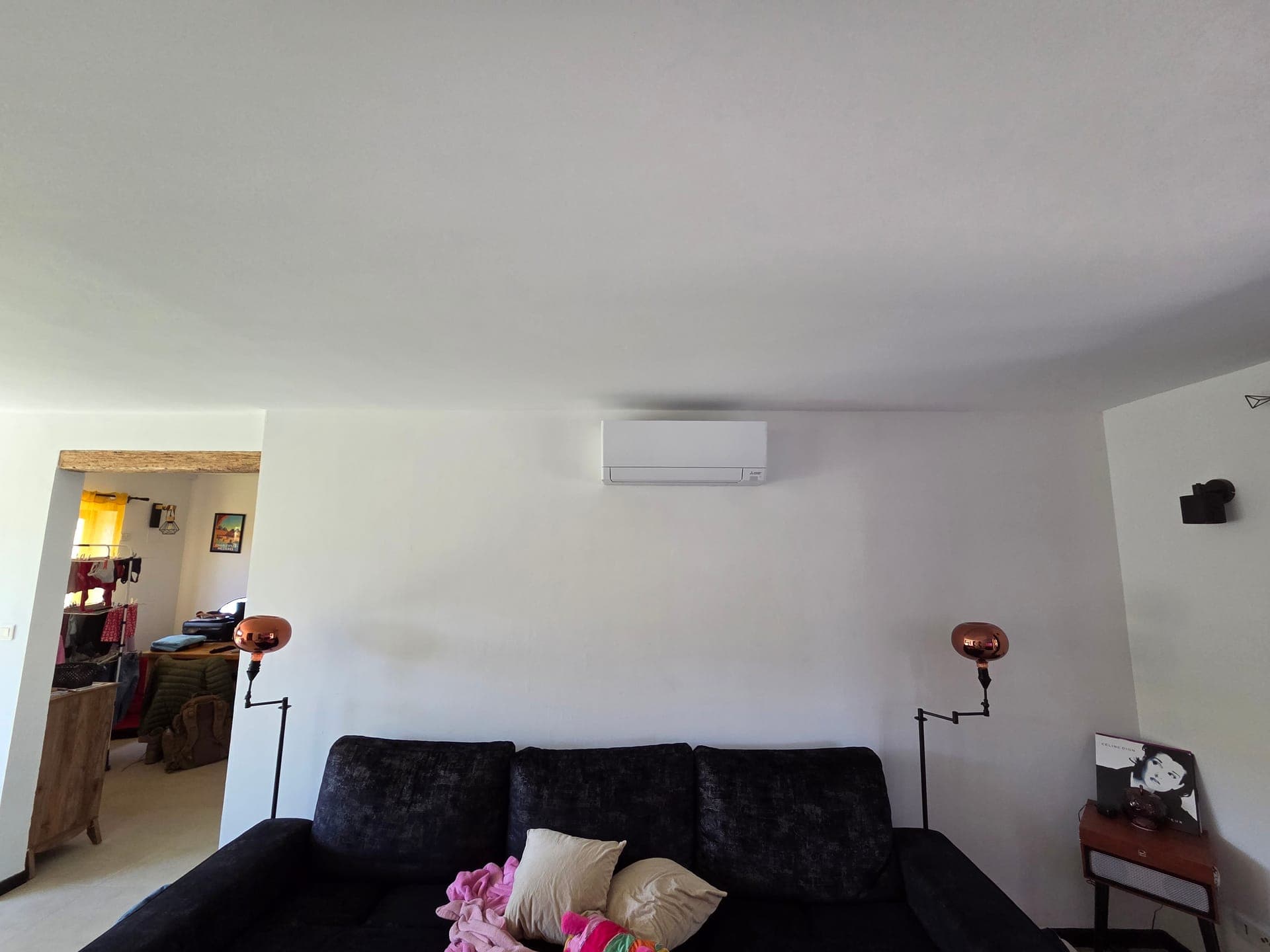Split mural de climatisation réversible intégré au-dessus d'un canapé de salon — pose à Pélissanne