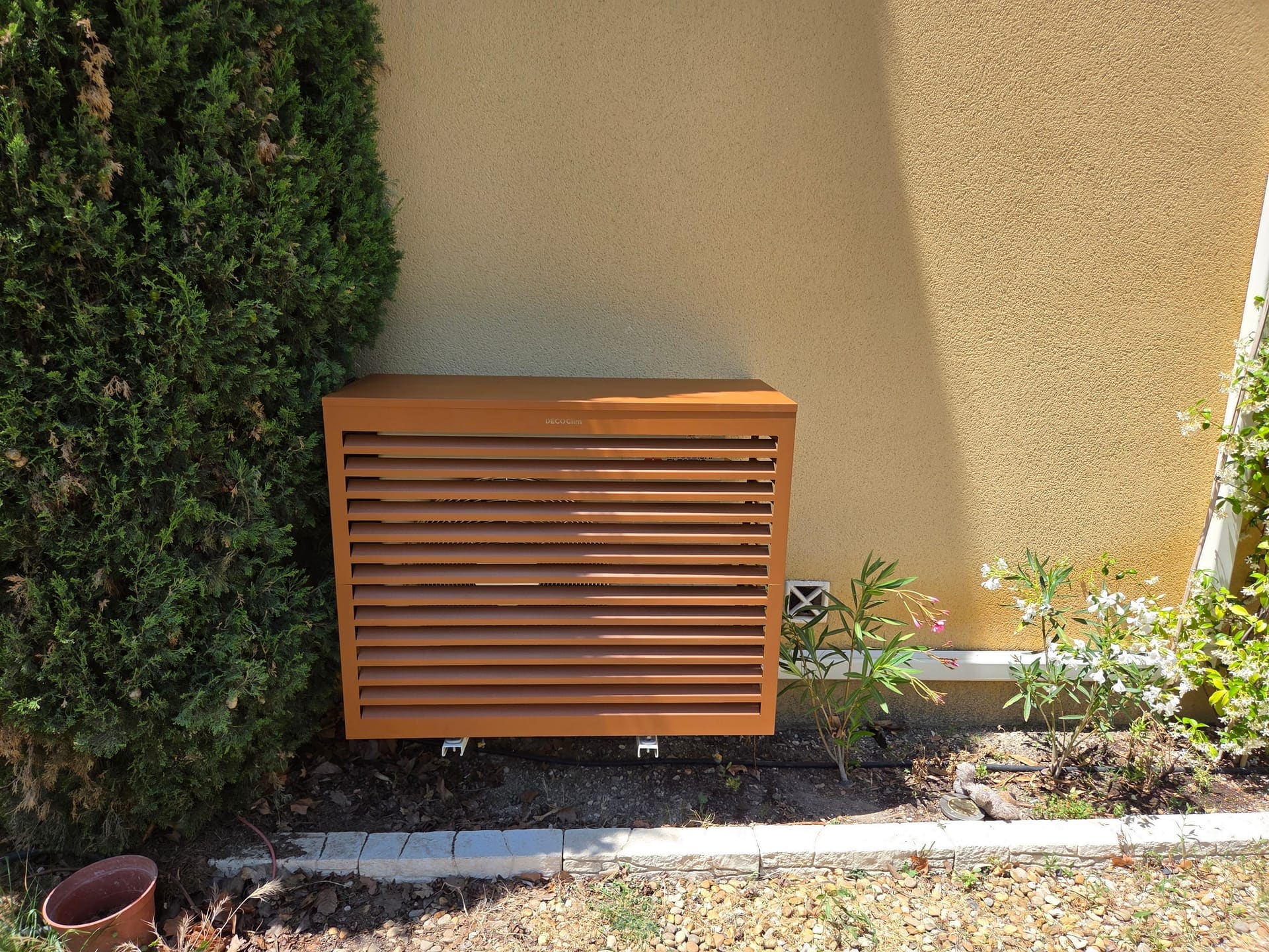 Cache aluminium à lattes ventilées habillant une unité extérieure de climatisation, intégration jardin méditerranéen